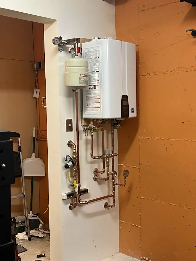 Plumbing technician inspecting water heater connections in West Boylston